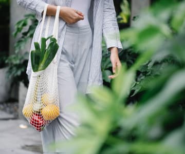 woman is walking with a bag full of fruits